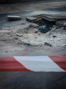 Close-up of a damaged pavement section with caution tape in Kyiv, Ukraine, showcasing urban decay.