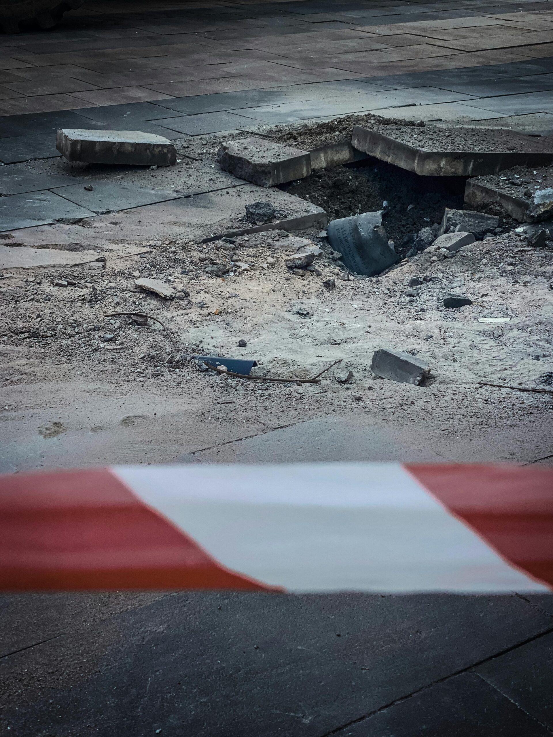 Close-up of a damaged pavement section with caution tape in Kyiv, Ukraine, showcasing urban decay.